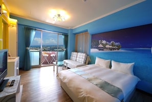 A hotel room with a large bed, a TV, a balcony with a view of the city, and a painting of a beach scene. - Each Family (Kaohsiung)
