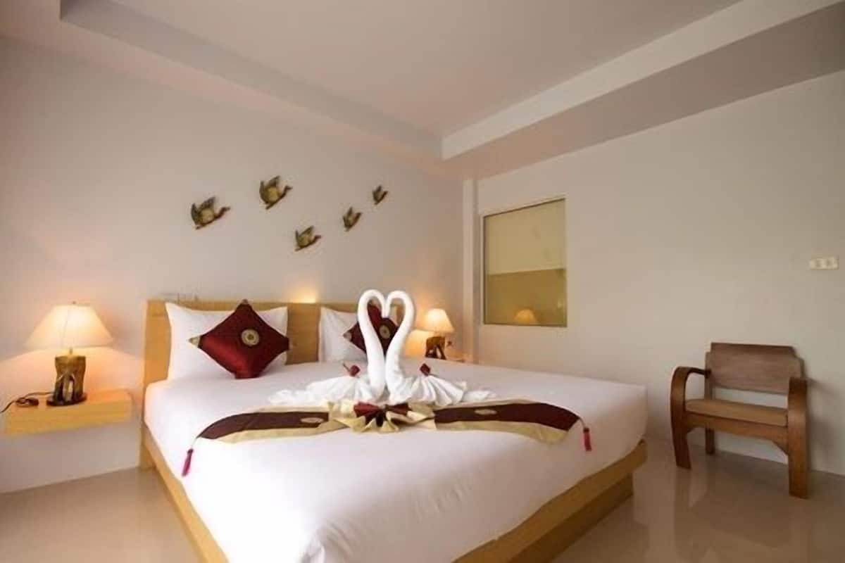 Une chambre d’hôtel avec un grand lit, deux tables de chevet, une chaise et des œuvres d’art murales.