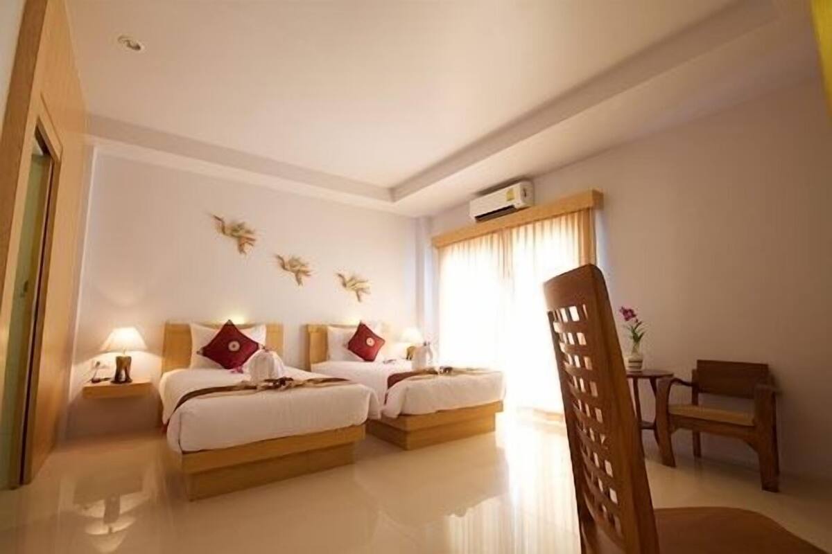 Une chambre d’hôtel avec deux lits, un bureau, une chaise et une fenêtre avec des rideaux.