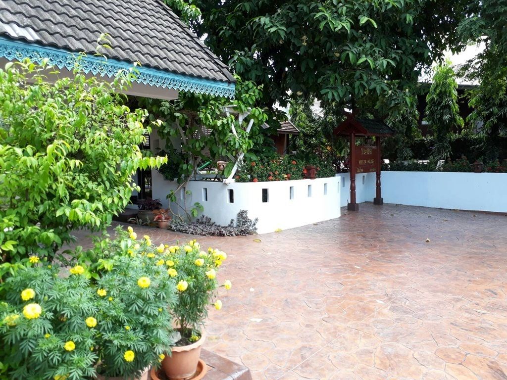 A courtyard with a tiled floor, potted plants, and a building with a tiled roof.