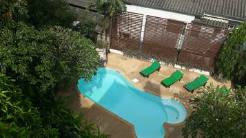 A swimming pool with two green lounge chairs and a wooden fence.