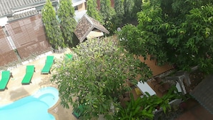 A rooftop pool area with green lounge chairs, a swimming pool, and surrounding greenery. - Wiriya House (Chiang Mai)