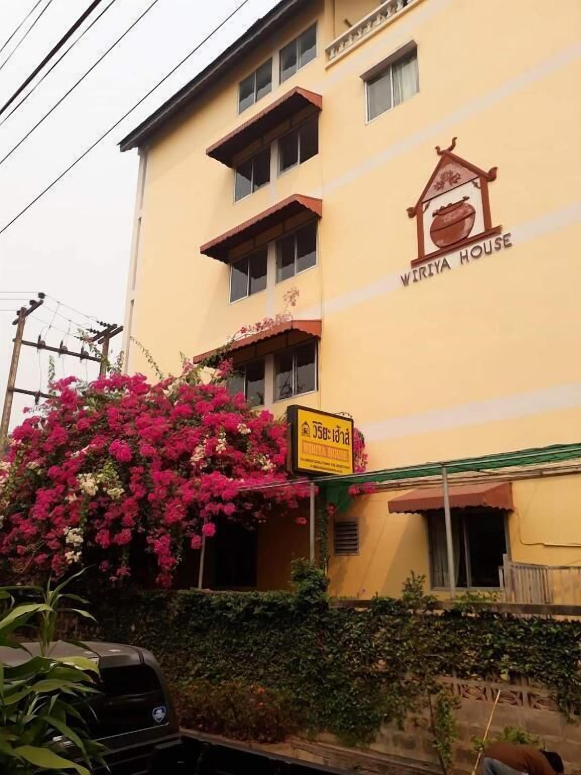 Ein Gebäude mit einem Schild, auf dem "WIRIYA HOUSE" steht, und einem weiteren Schild in einer anderen Sprache.
