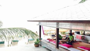 Uma área de lounge no terraço com bancos e cadeiras de descanso de madeira, alguns com almofadas cor-de-rosa.