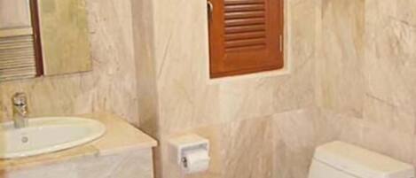 Un baño con lavamanos, inodoro y espejo.