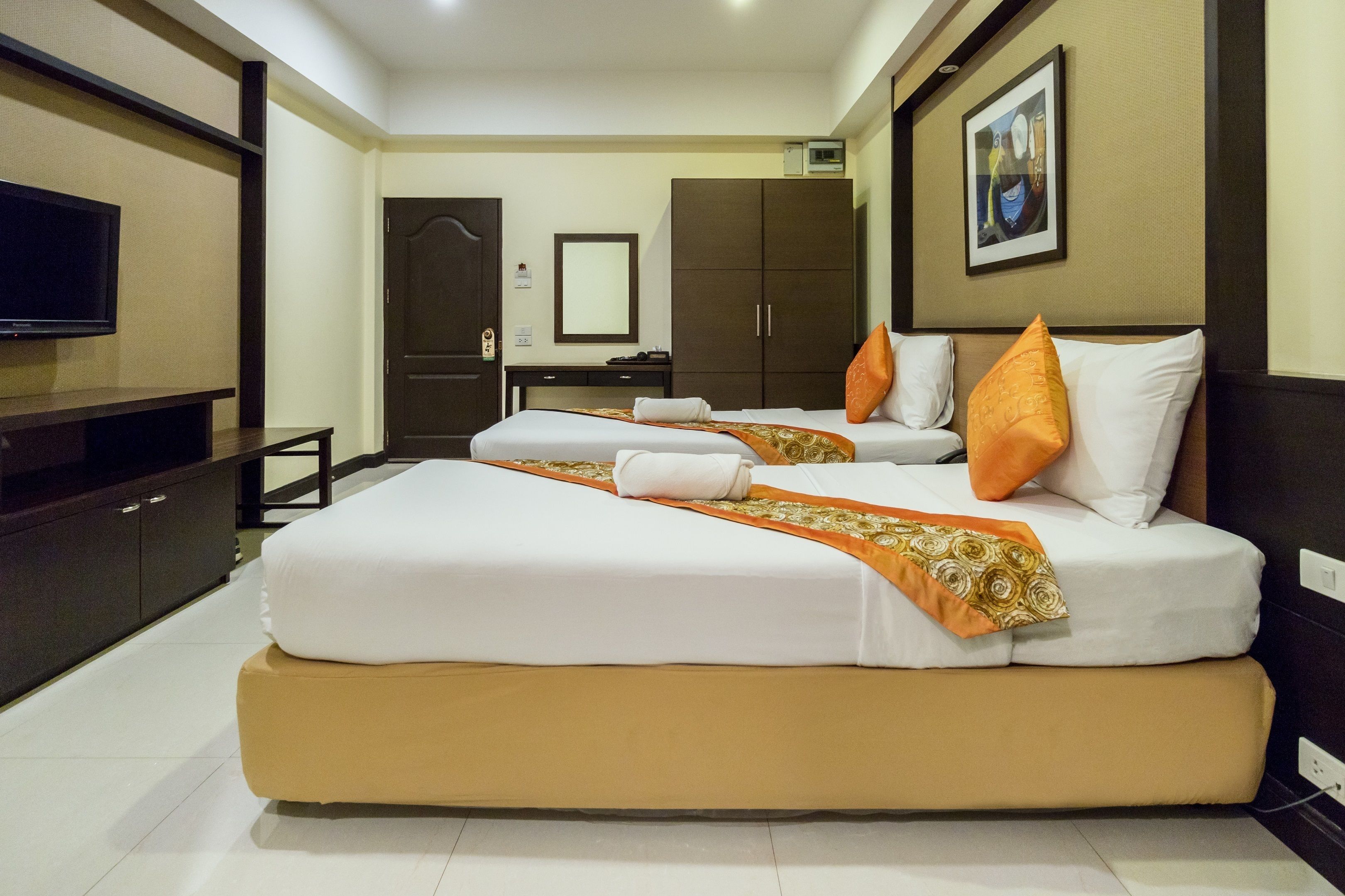 Una habitación de hotel con dos camas, televisión, escritorio y armario.