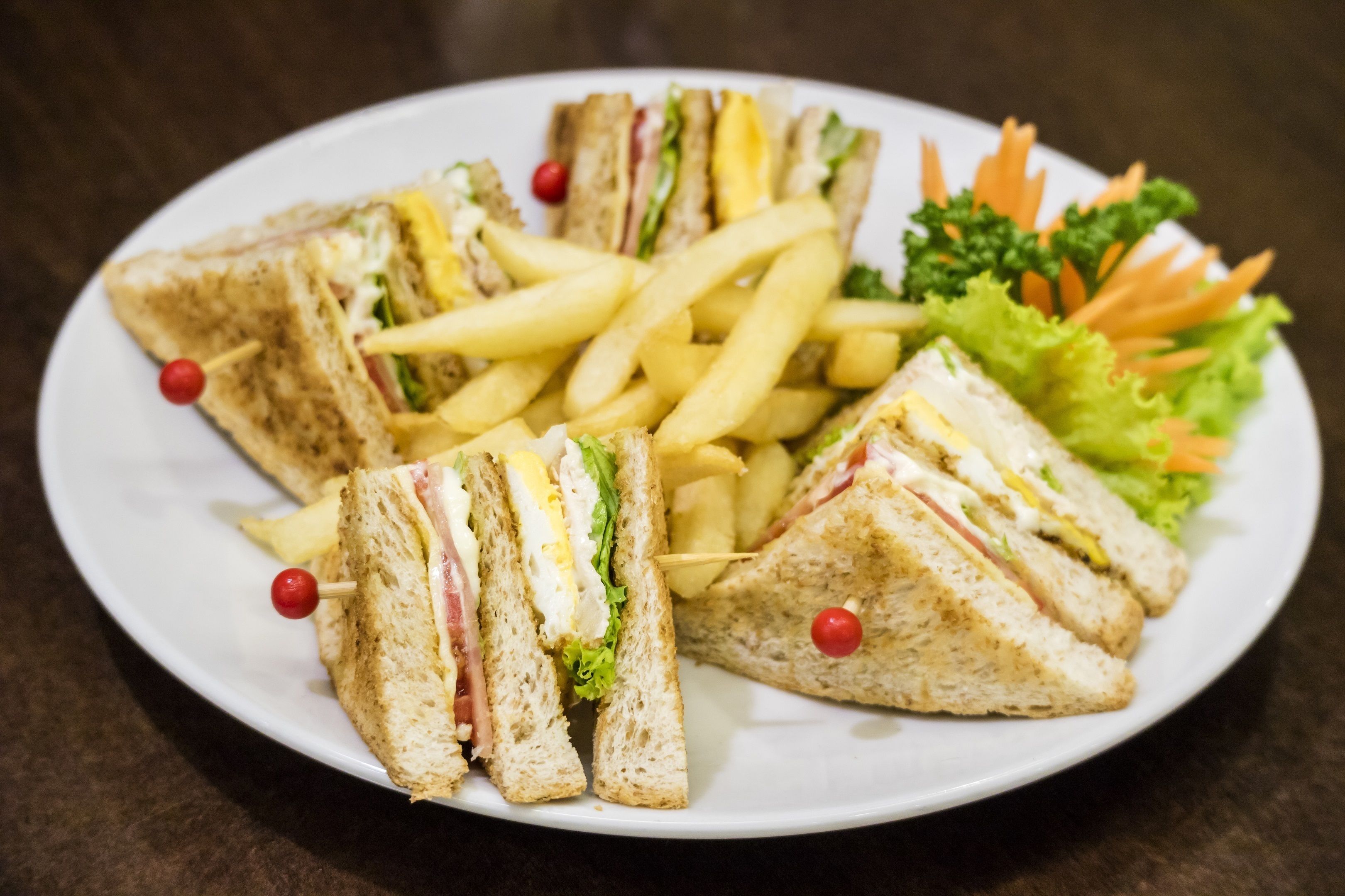 A plate with sandwiches, French fries, and vegetables.