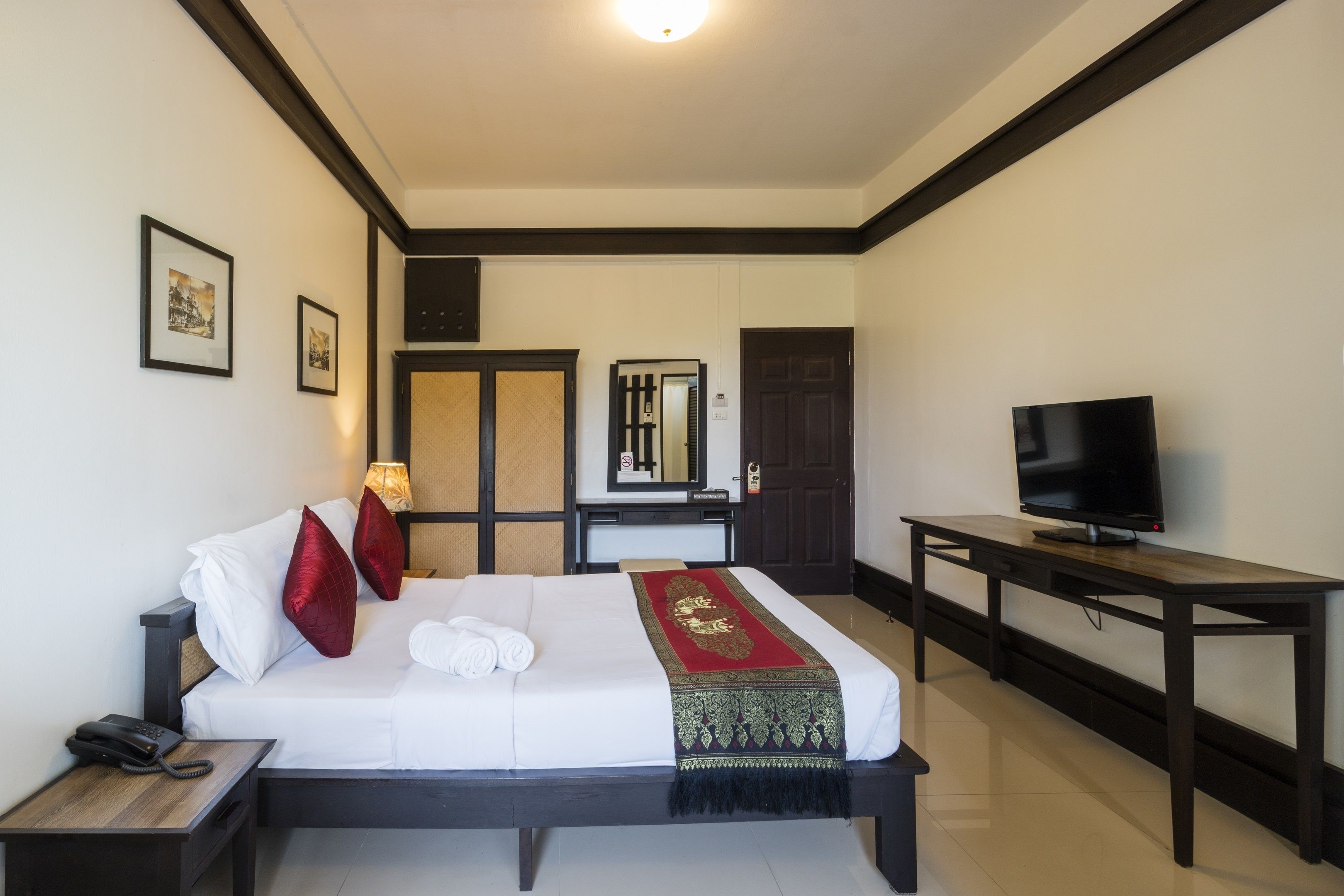 A hotel room with a bed, a TV, a desk, and a mirror.