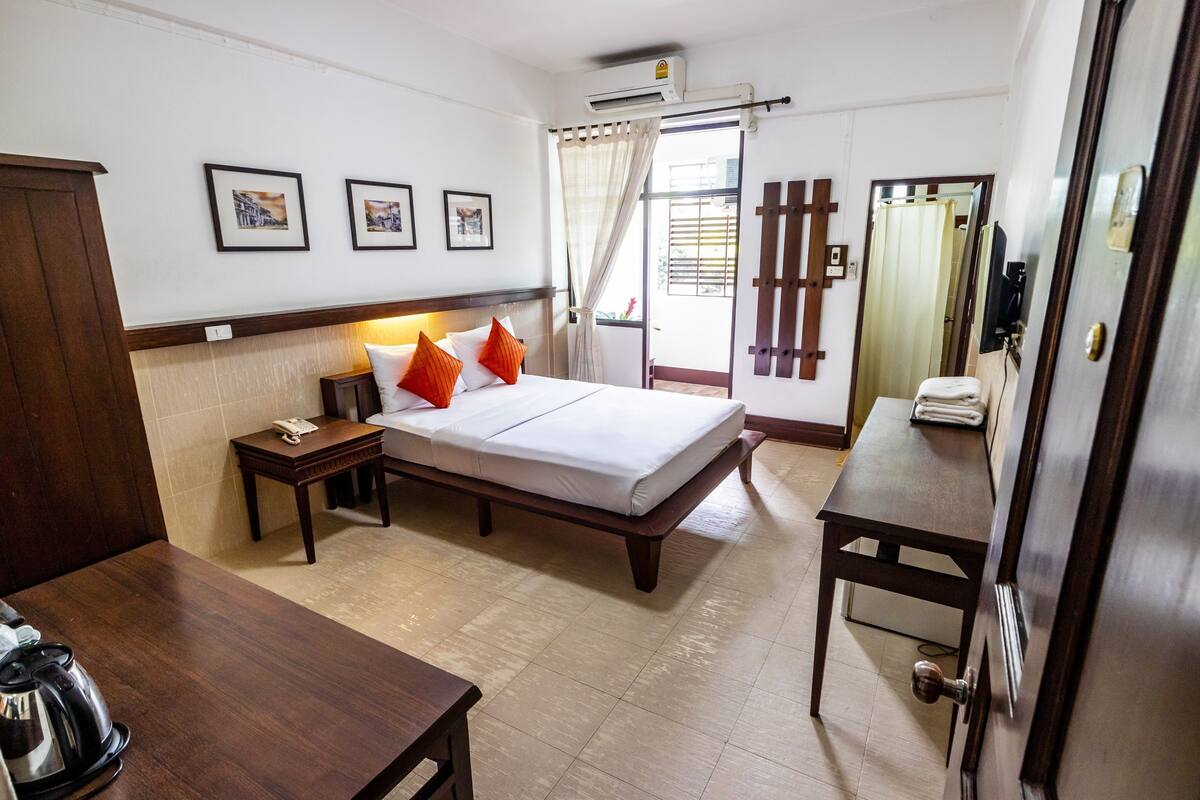 Una habitación de hotel con una cama, una mesita de noche y una pequeña mesa con una tetera.