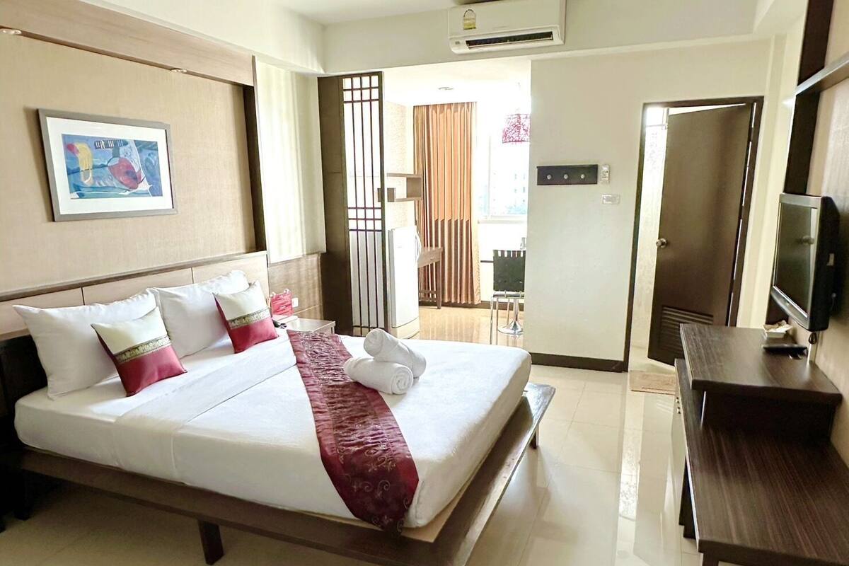 Una habitación de hotel con una cama, televisión y puerta.
