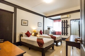 Een hotelkamer met twee bedden, een bureau, een stoel, een tafel en een airconditioning.