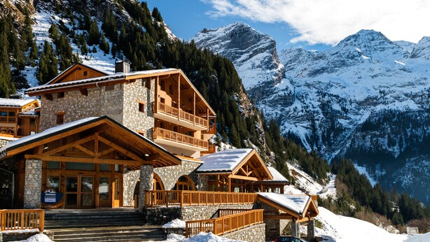 A multi-story stone building with wooden balconies, set against a snowy mountain backdrop. - Résidence Lagrange Vacances Les Hauts de la Vanoise (Pralognan-la-Vanoise)