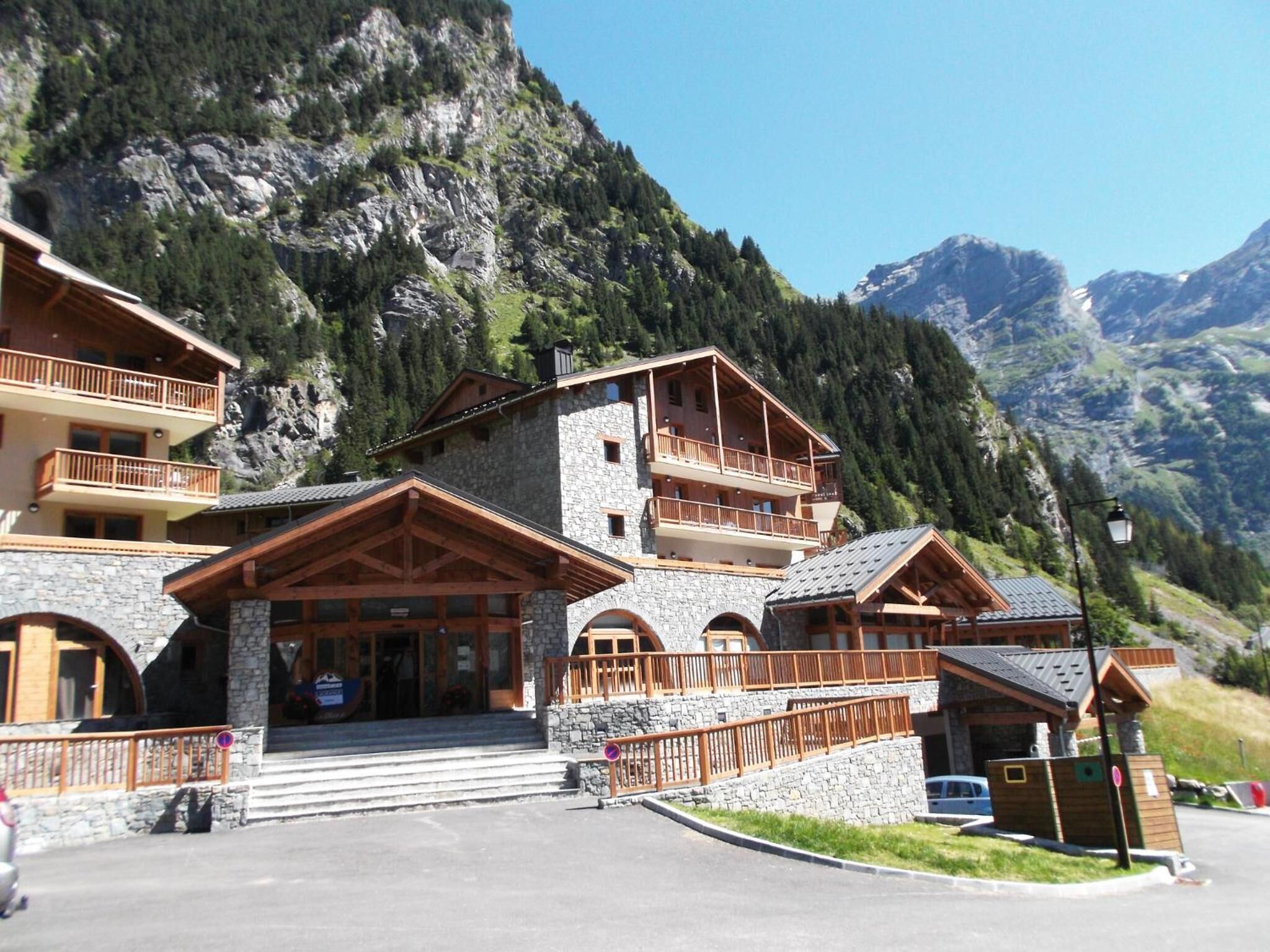 A mountain lodge with multiple balconies, stone walls, and a view of the surrounding mountains.