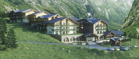 A mountain lodge with multiple wooden buildings, stone walls, and a stone bridge.