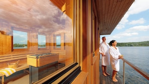 A wooden cabin with a sauna, a wooden deck, and a view of a lake. - INSELHOTEL Potsdam - Hermannswerder (Potsdam)