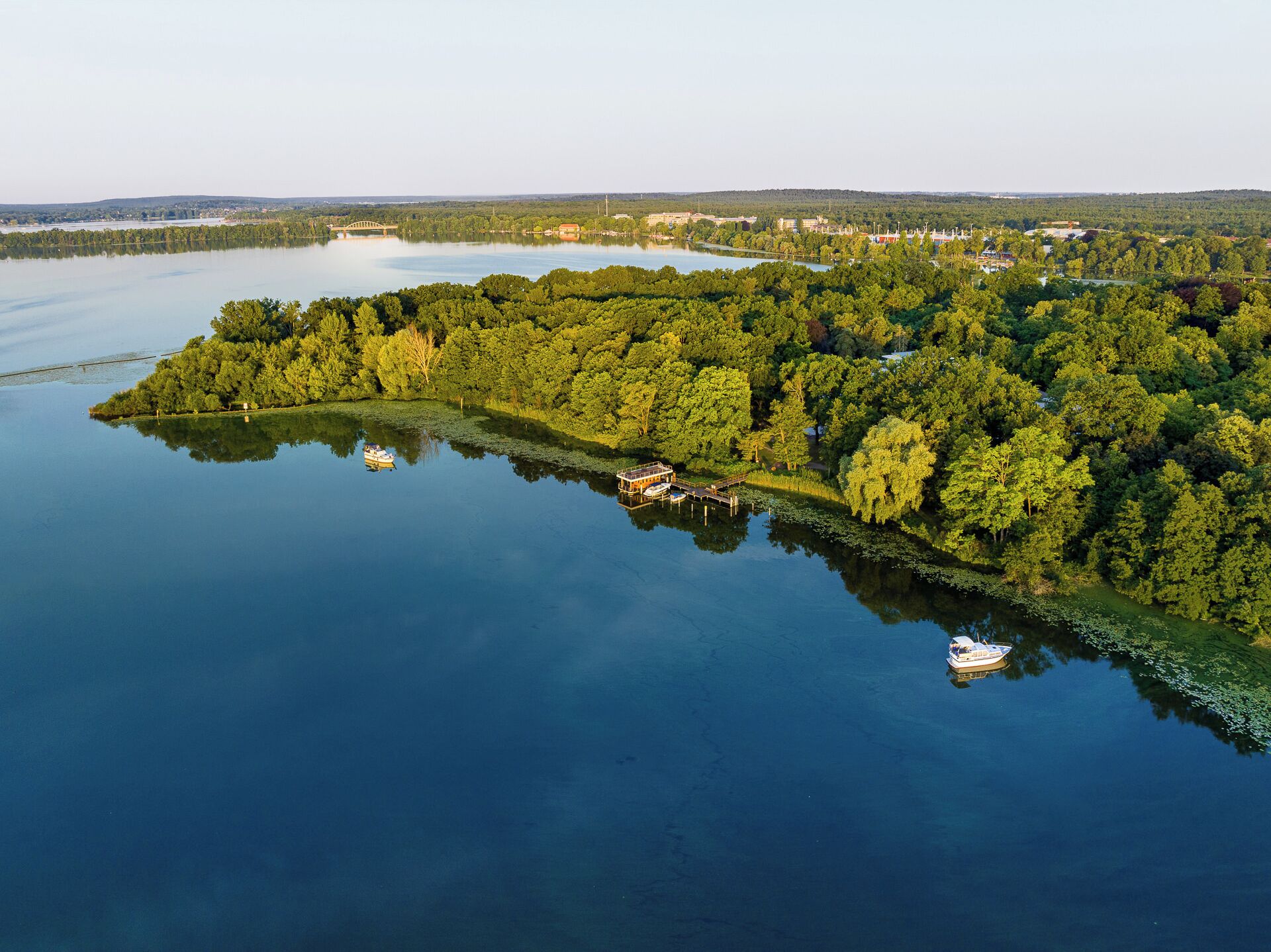 Vista aérea de un lago con una pequeña isla que tiene un muelle y un bote.