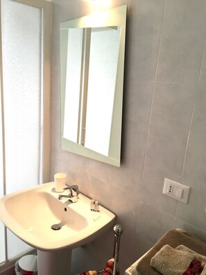Un baño con lavamanos, espejo y toallero.