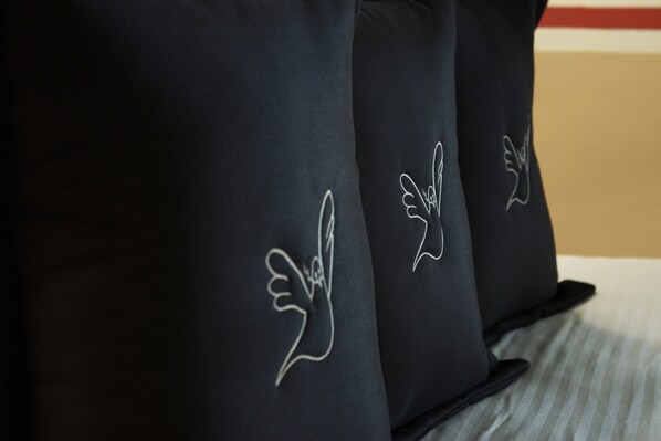 Primer plano de almohadas negras con diseños de ángeles bordados en blanco.