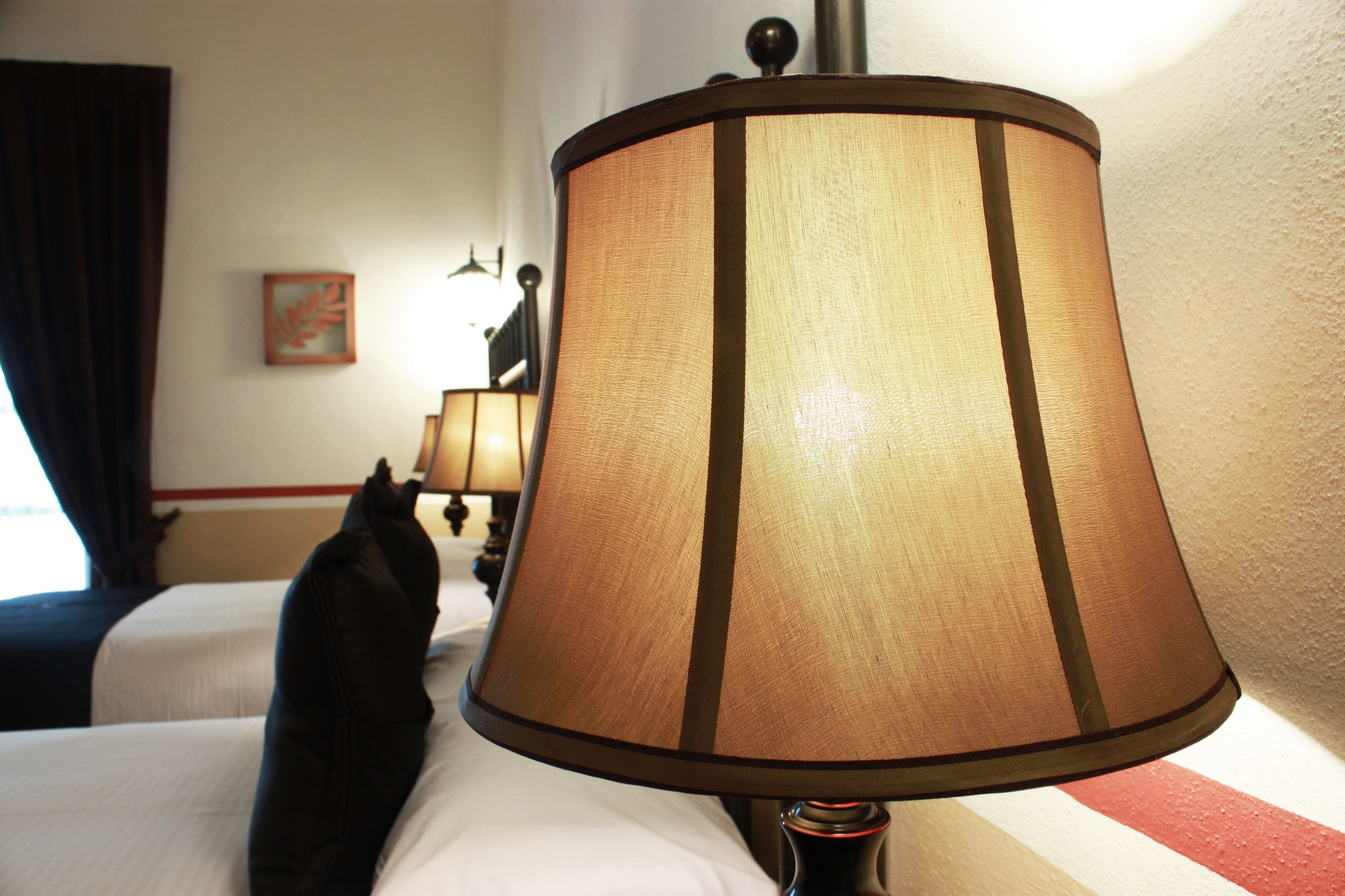 A hotel room with a bed, a lamp, and a painting on the wall.