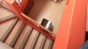 A staircase with red railings leading to a landing with a small sink and a toilet. - Hotel Santa Regina (Guanajuato)