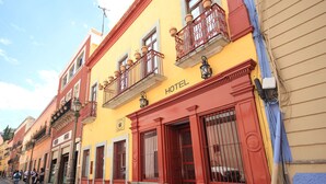 A hotel with a red and yellow facade, a balcony with red railings, and a sign indicating the hotel's name. - Hotel Santa Regina (Guanajuato)