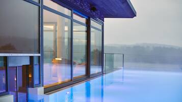 A modern building with large glass windows overlooking a pool.