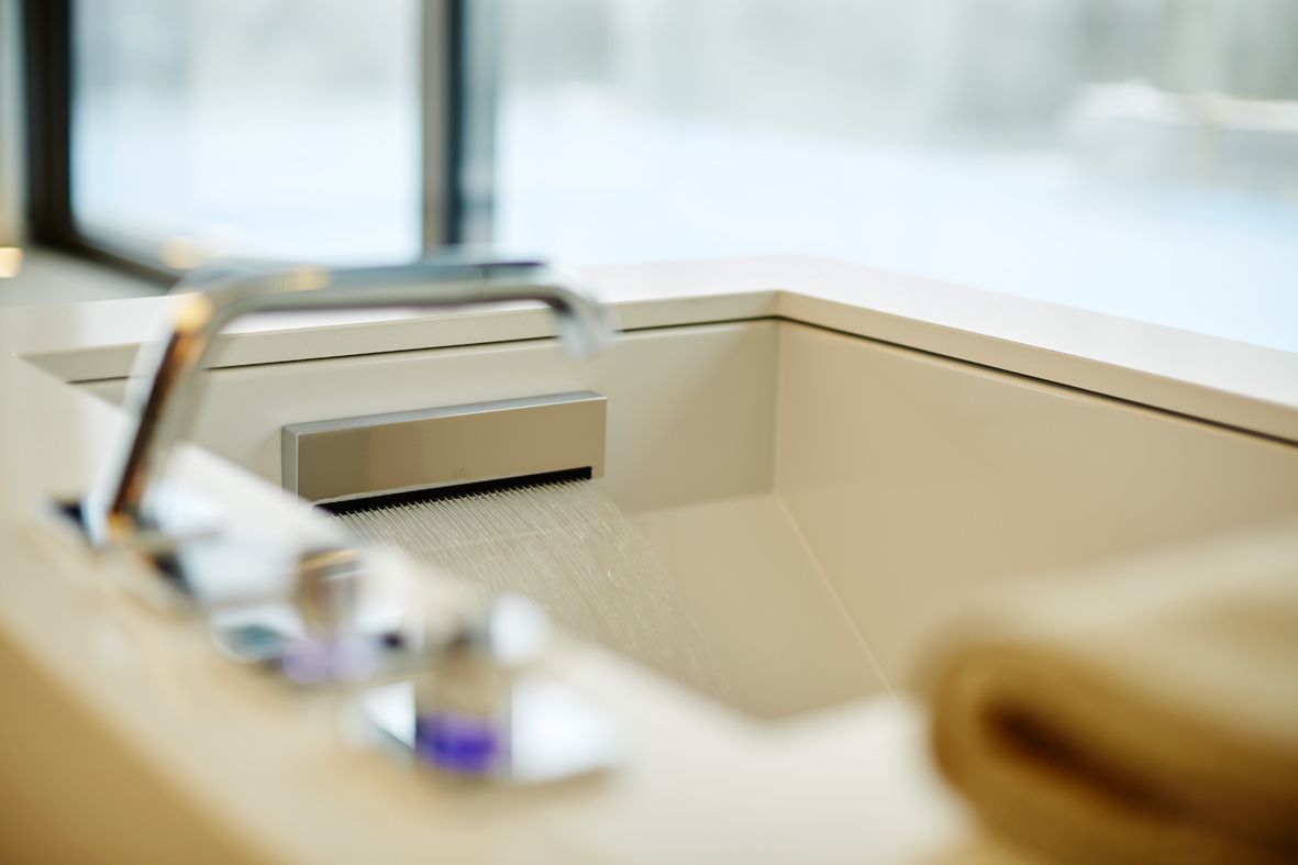 A bathroom with a modern sink, a window, and a shower area.