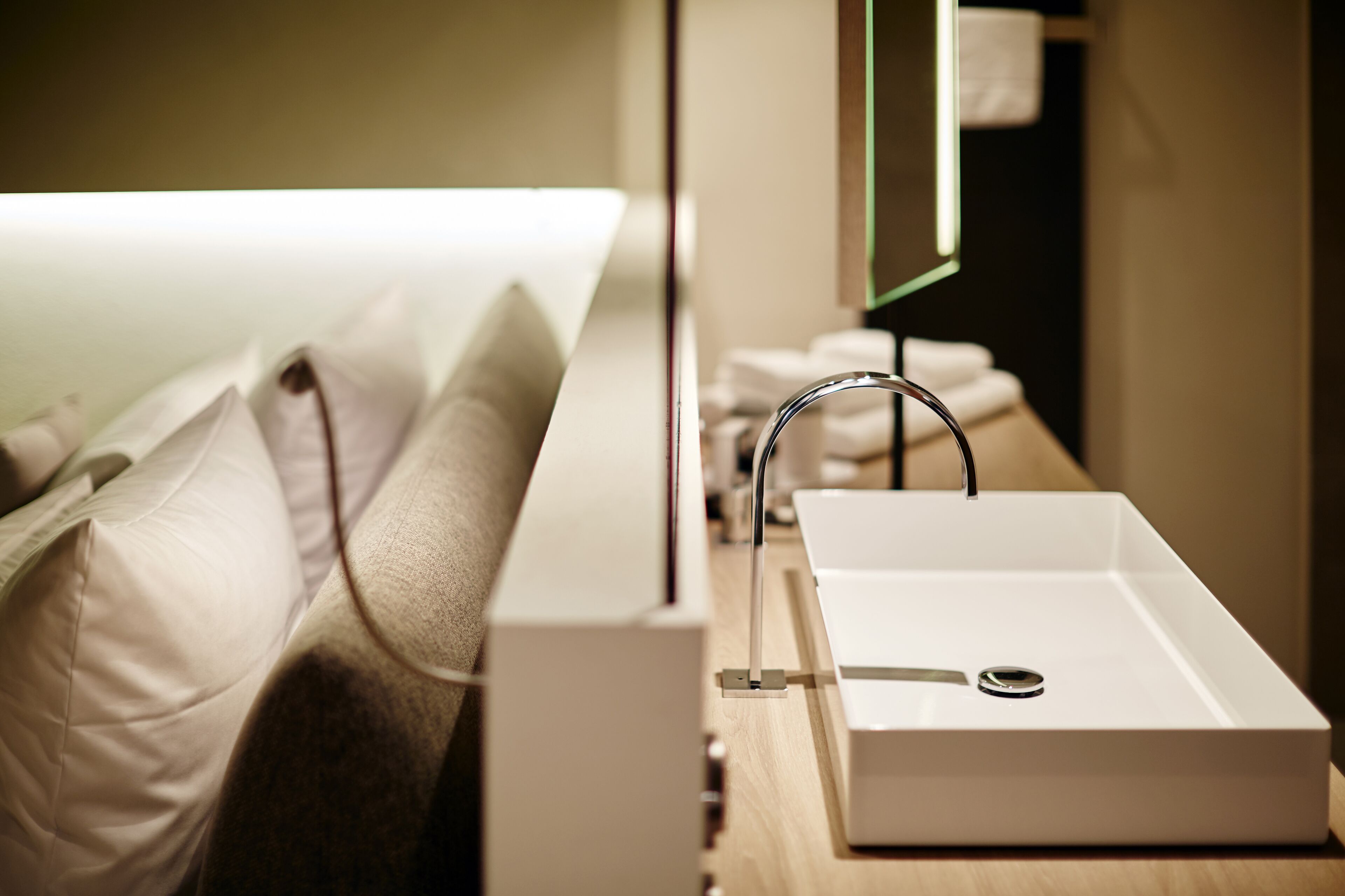 Un bagno d'hotel con un lavandino bianco, uno specchio e un piano d'appoggio in legno.