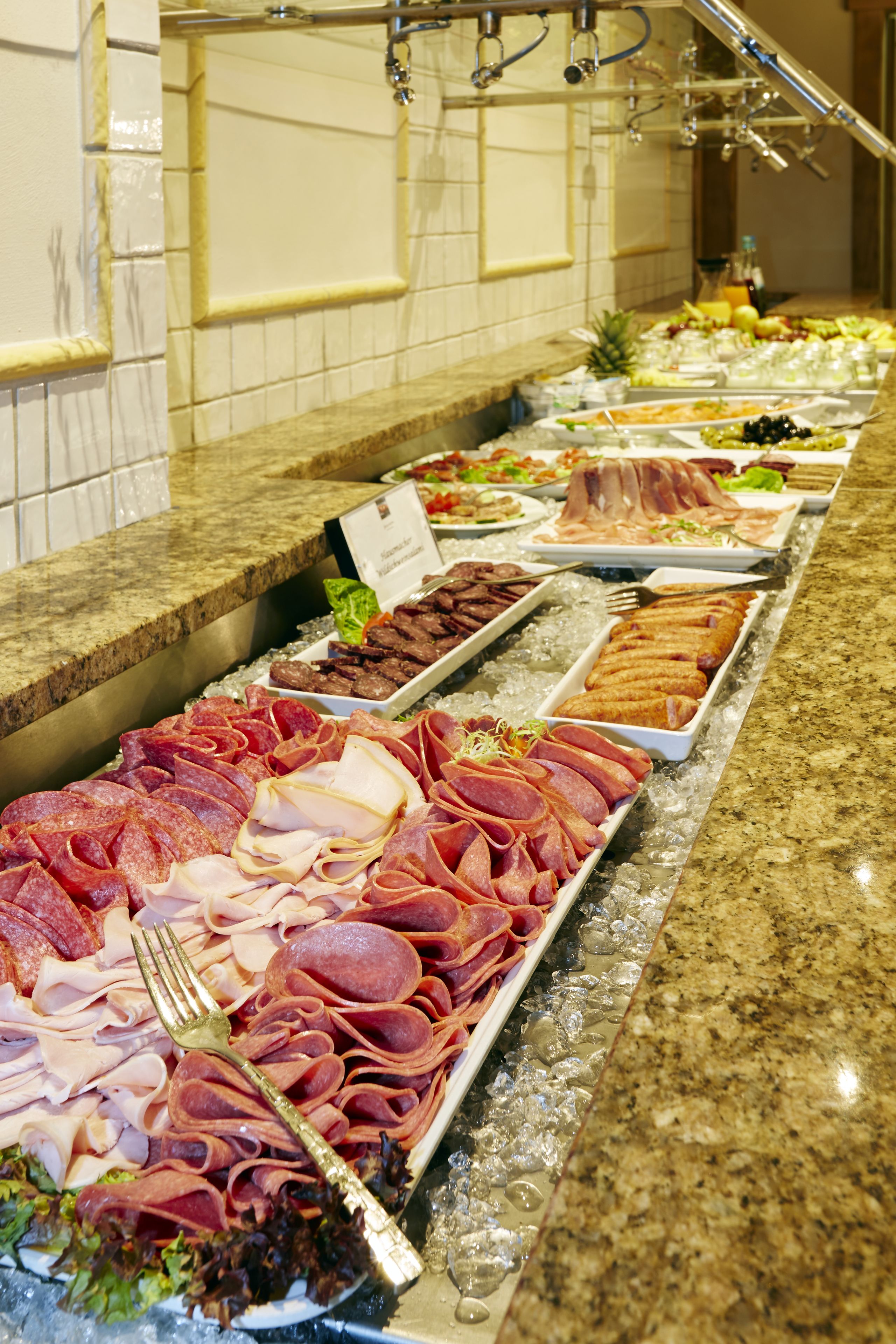 A buffet with various cold cuts, cheeses, and fruits.