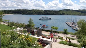Vista al lago con un muelle, un parque infantil y un puerto deportivo con barcos.