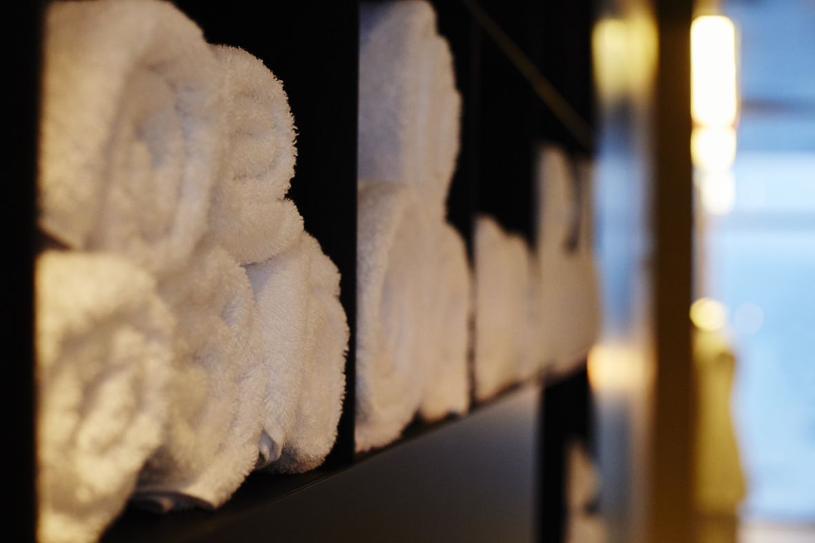 Una hilera de toallas blancas dobladas cuidadosamente en una pared, probablemente en un hotel o alojamiento similar.