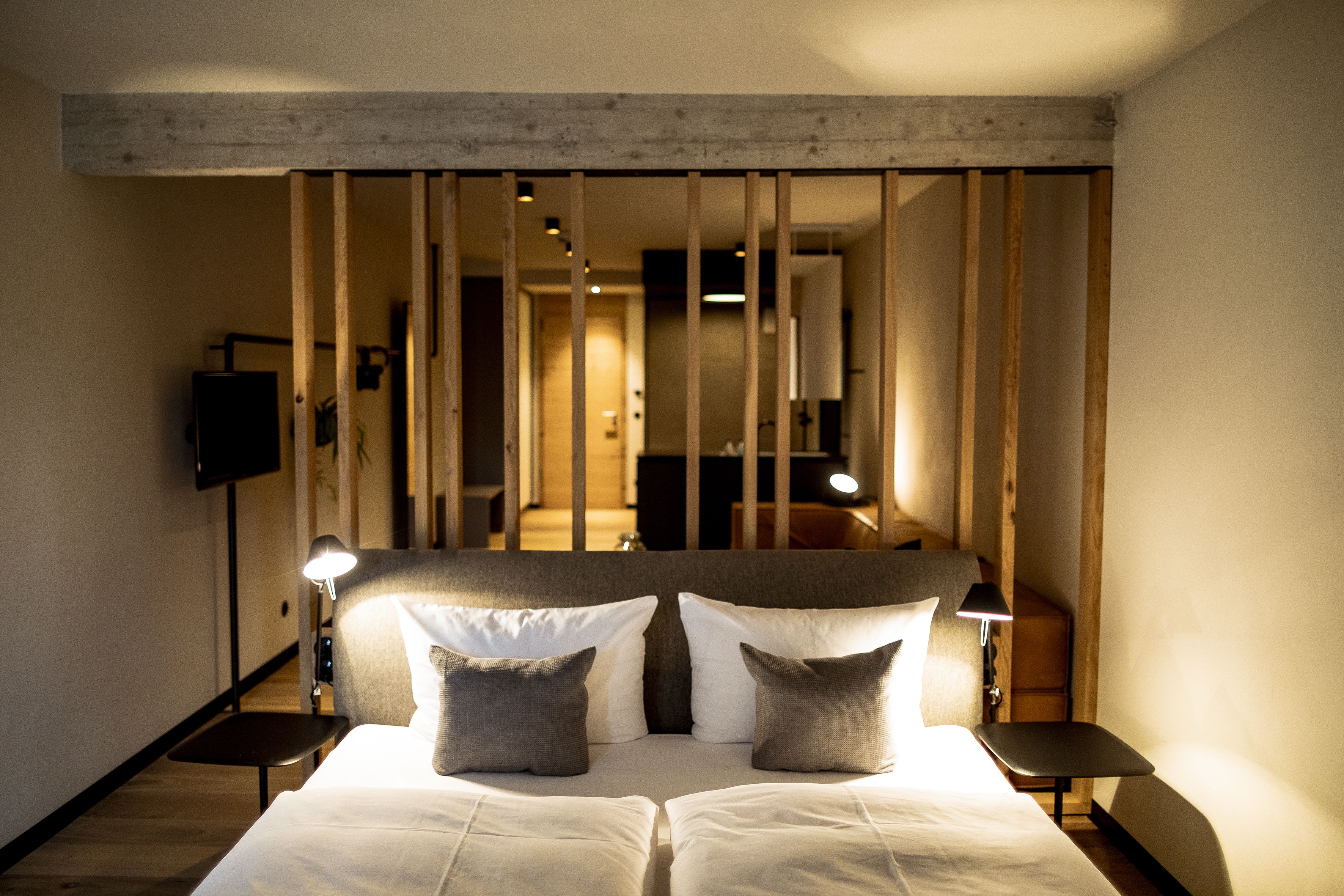 Ein Hotelzimmer mit einem großen Bett, zwei Nachttischen, einem Fernseher und einer Holzwand.