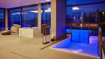A modern hotel lobby with a large glass wall, a reception desk, and a seating area with a bench and a small table.
