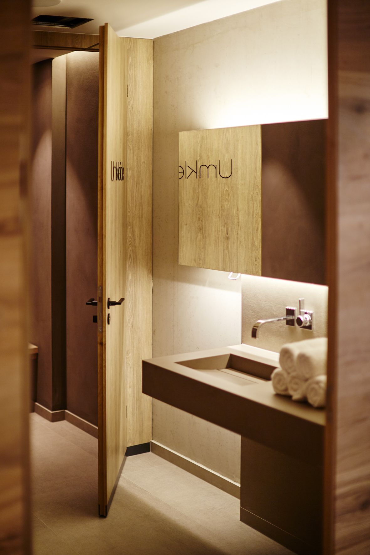 A modern bathroom with a wooden vanity, a sink, and a mirror.
