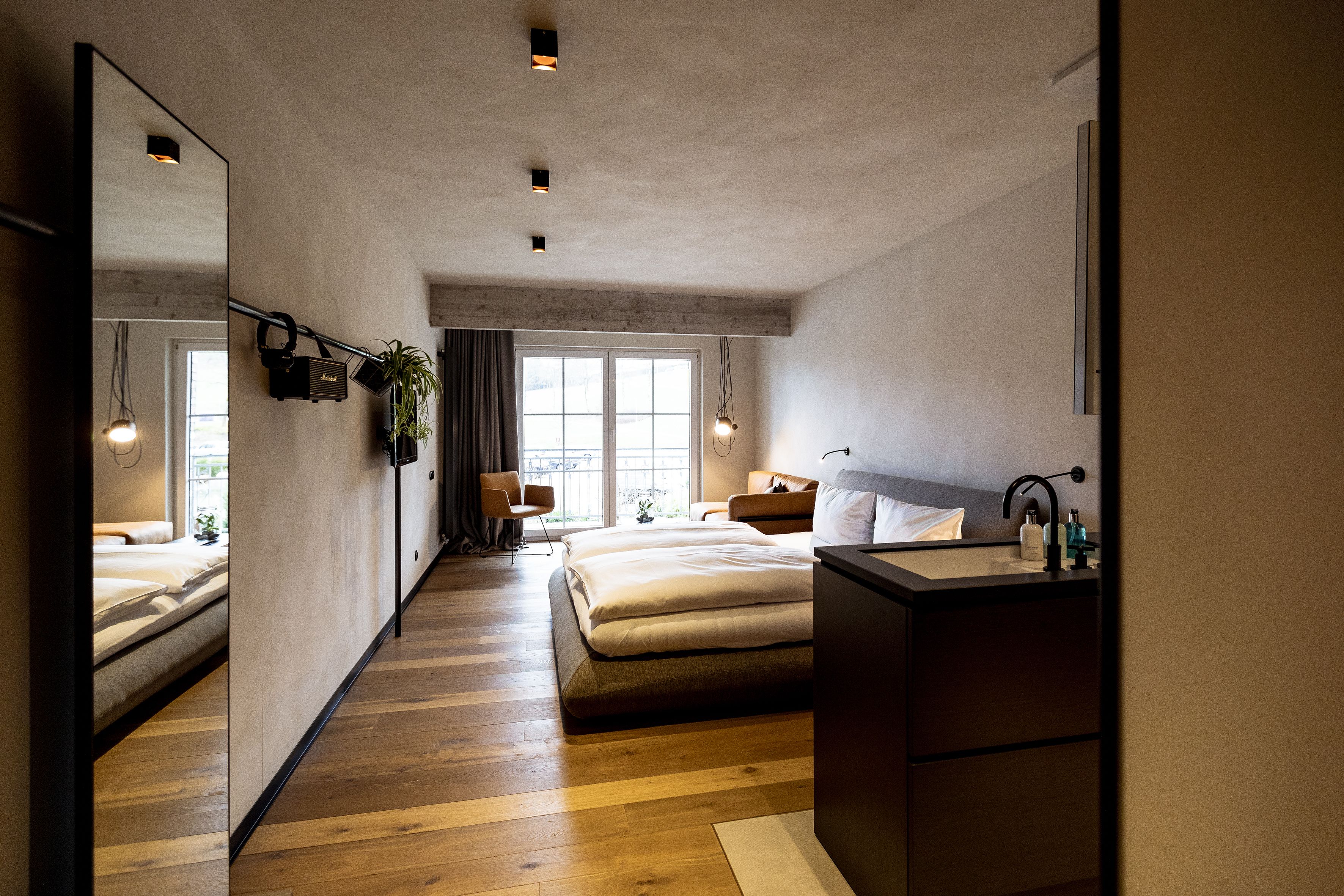 Un dormitorio moderno con una cama grande, una mesita de noche, un espejo y una ventana.