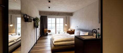 Un dormitorio moderno con una cama grande, una mesita de noche, un espejo y una ventana.