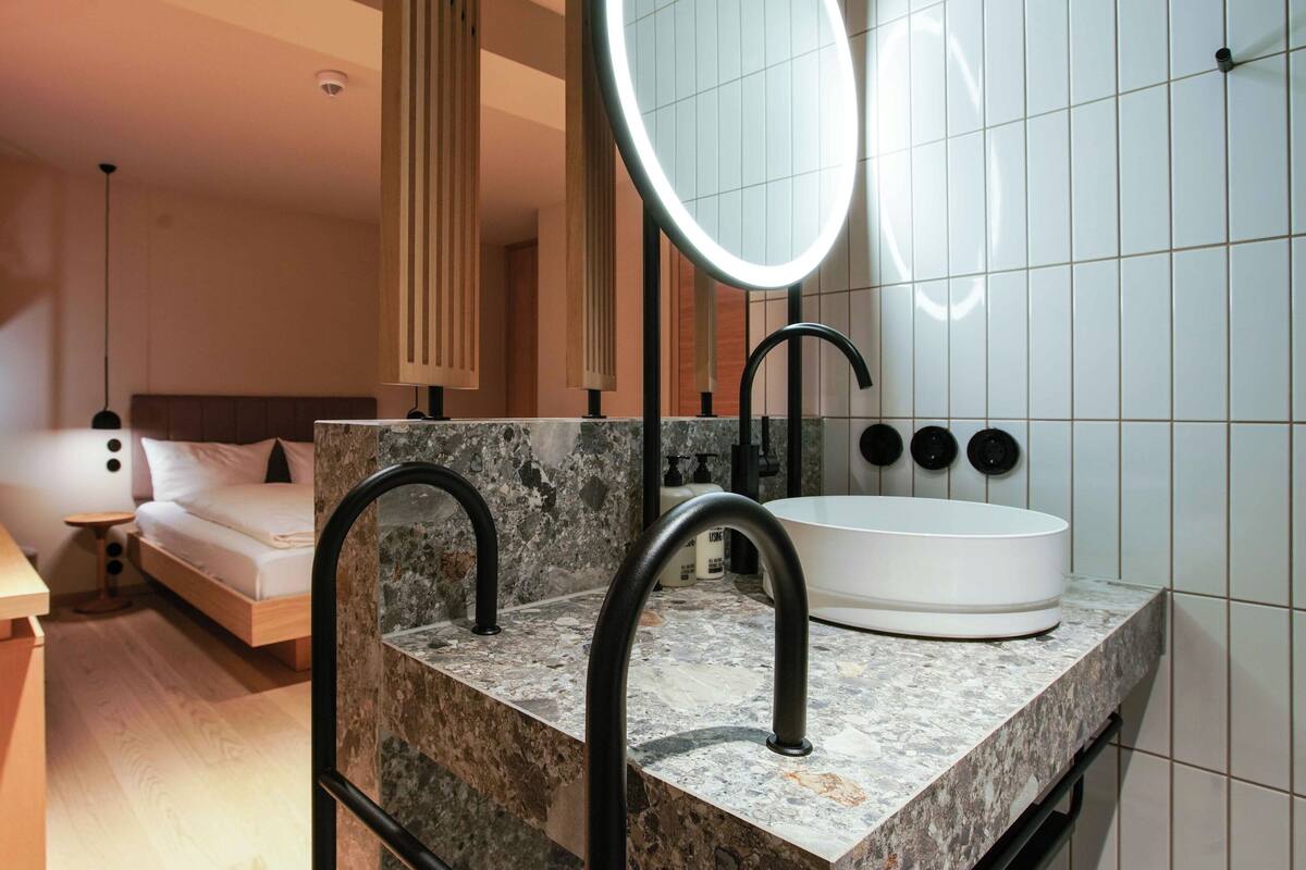 A modern bathroom with a marble countertop, a white sink, and a large mirror.