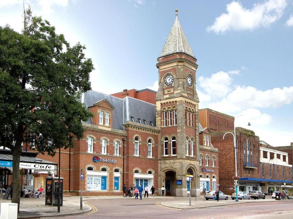 A historic building with a clock tower, a cafe, and a Travelodge hotel.