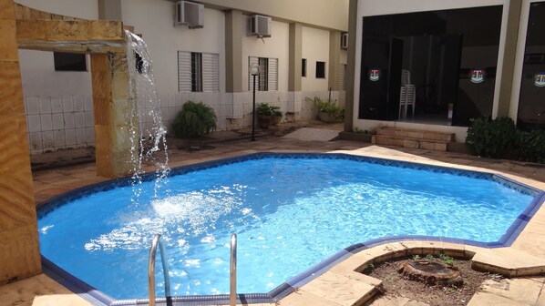 Una piscina al aire libre, sillones reclinables de piscina