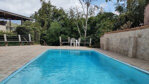 Une piscine rectangulaire à l’eau d’un bleu limpide, entourée d’une terrasse carrelée et d’un mur en béton.