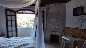 Une chambre avec un lit, une table, une chaise, un téléviseur et une vue sur l’extérieur.