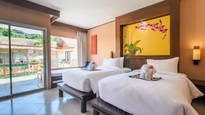 A hotel room with two beds, a balcony with a view, and a large floral painting on the wall.