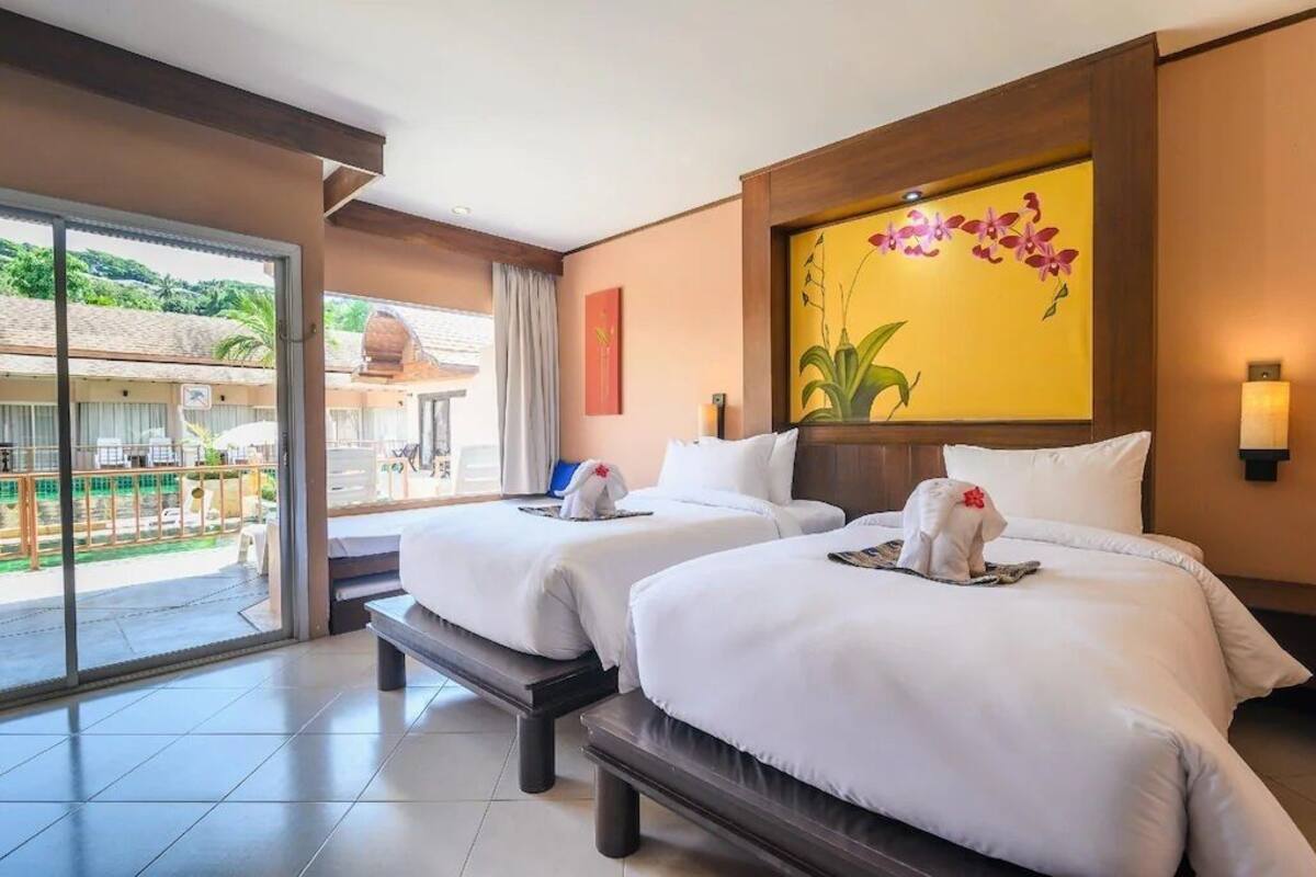 Una habitación de hotel con dos camas, un balcón con vistas y un cuadro grande con motivos florales en la pared.