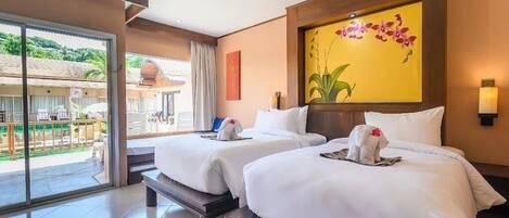 A hotel room with two beds, a balcony with a view, and a large floral painting on the wall.