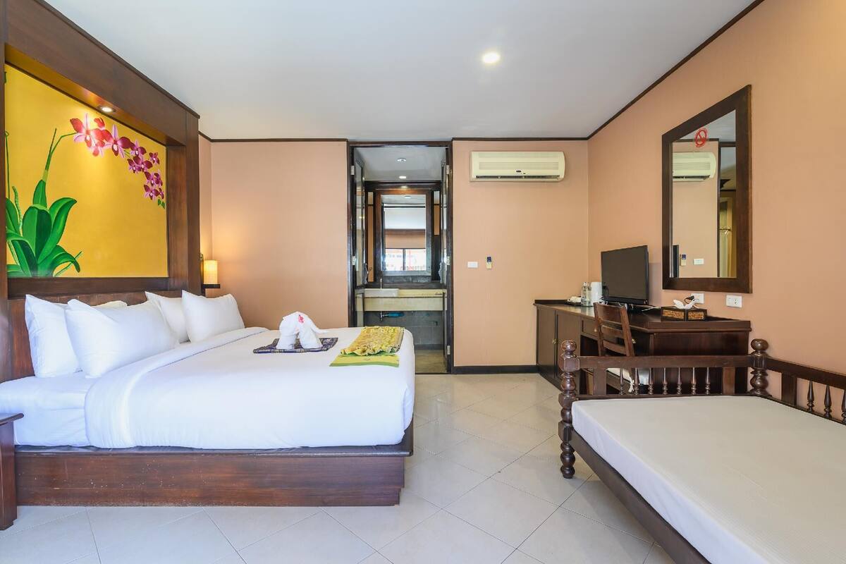 Una habitación de hotel con una cama grande, un escritorio, una silla, un televisor y un equipo de aire acondicionado.