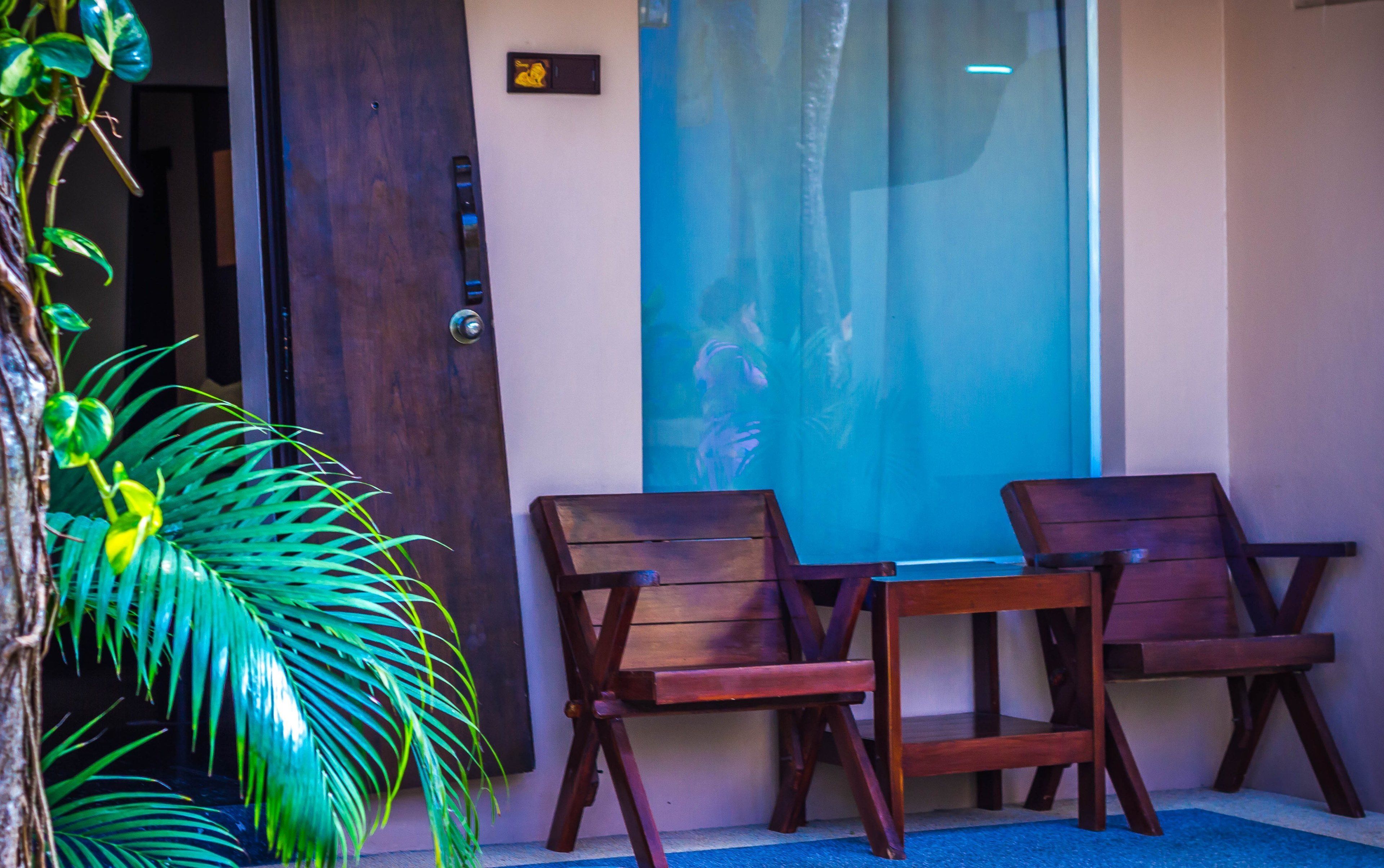 A wooden door with a keyhole, a glass window with a blue tint, and two wooden chairs with a blue carpet.