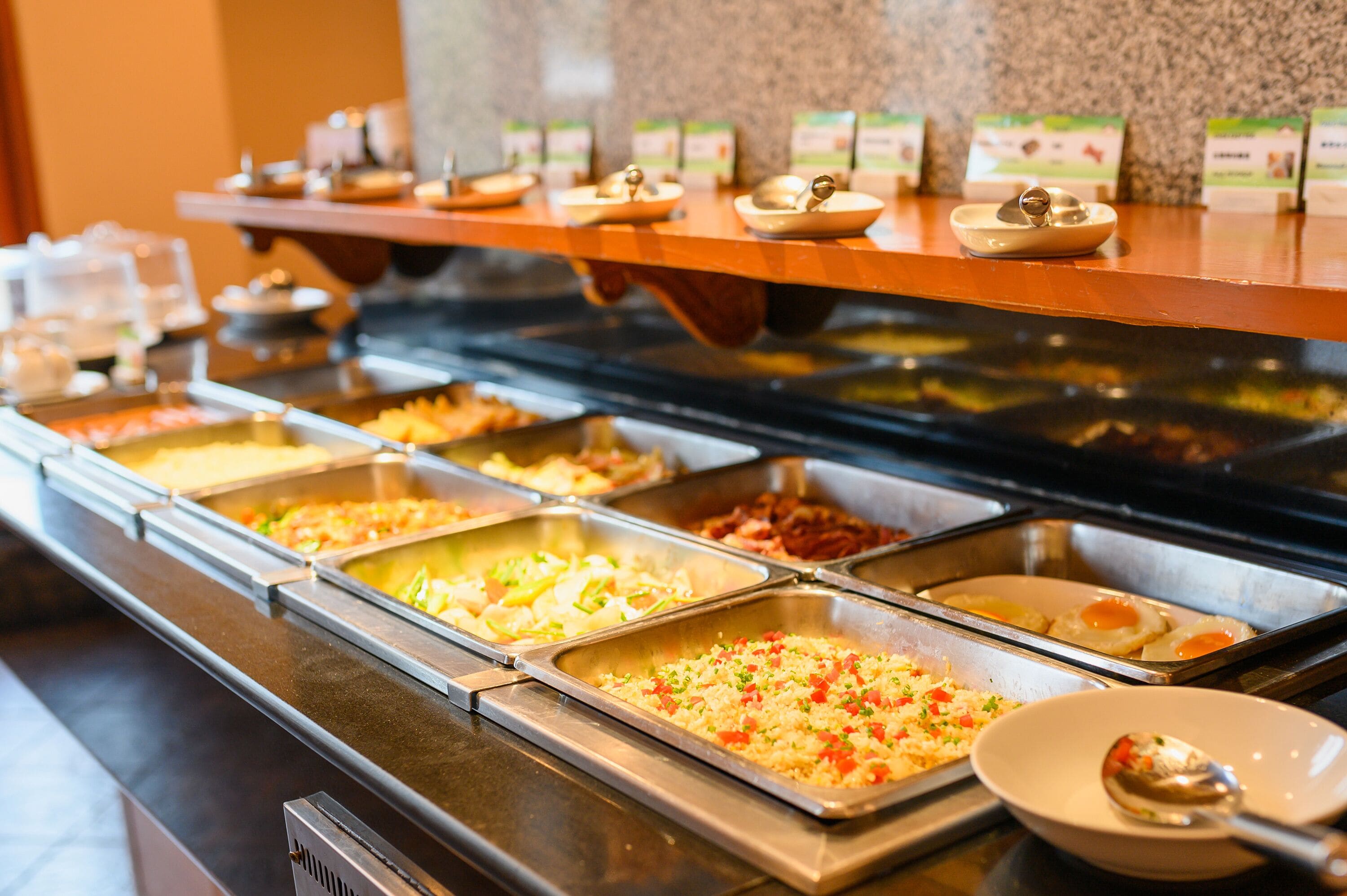 Un bufé con diversas opciones de comida, incluyendo arroz, huevos y carnes.