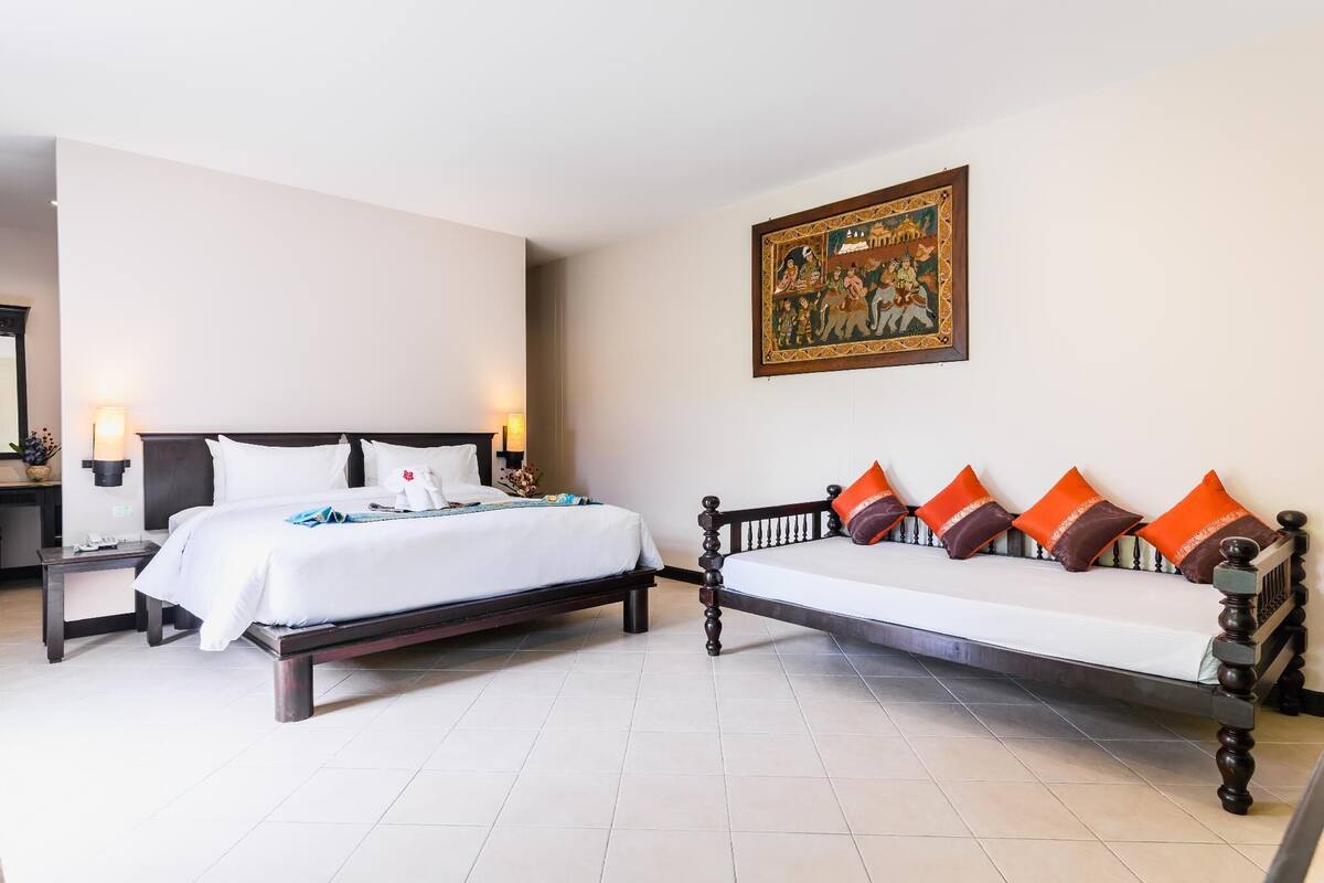 Una habitación de hotel con una cama grande, un sofá y un cuadro colgado en la pared.