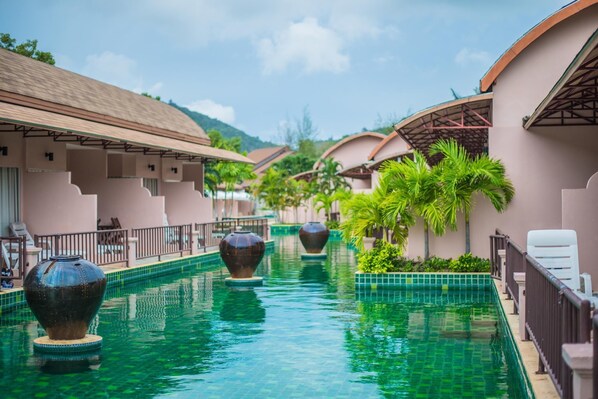 A pool area with large decorative vases, lounge chairs, and a tiled walkway.