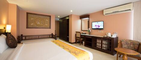 Habitación de hotel con una cama grande, un escritorio, una silla, un televisor y un aire acondicionado.